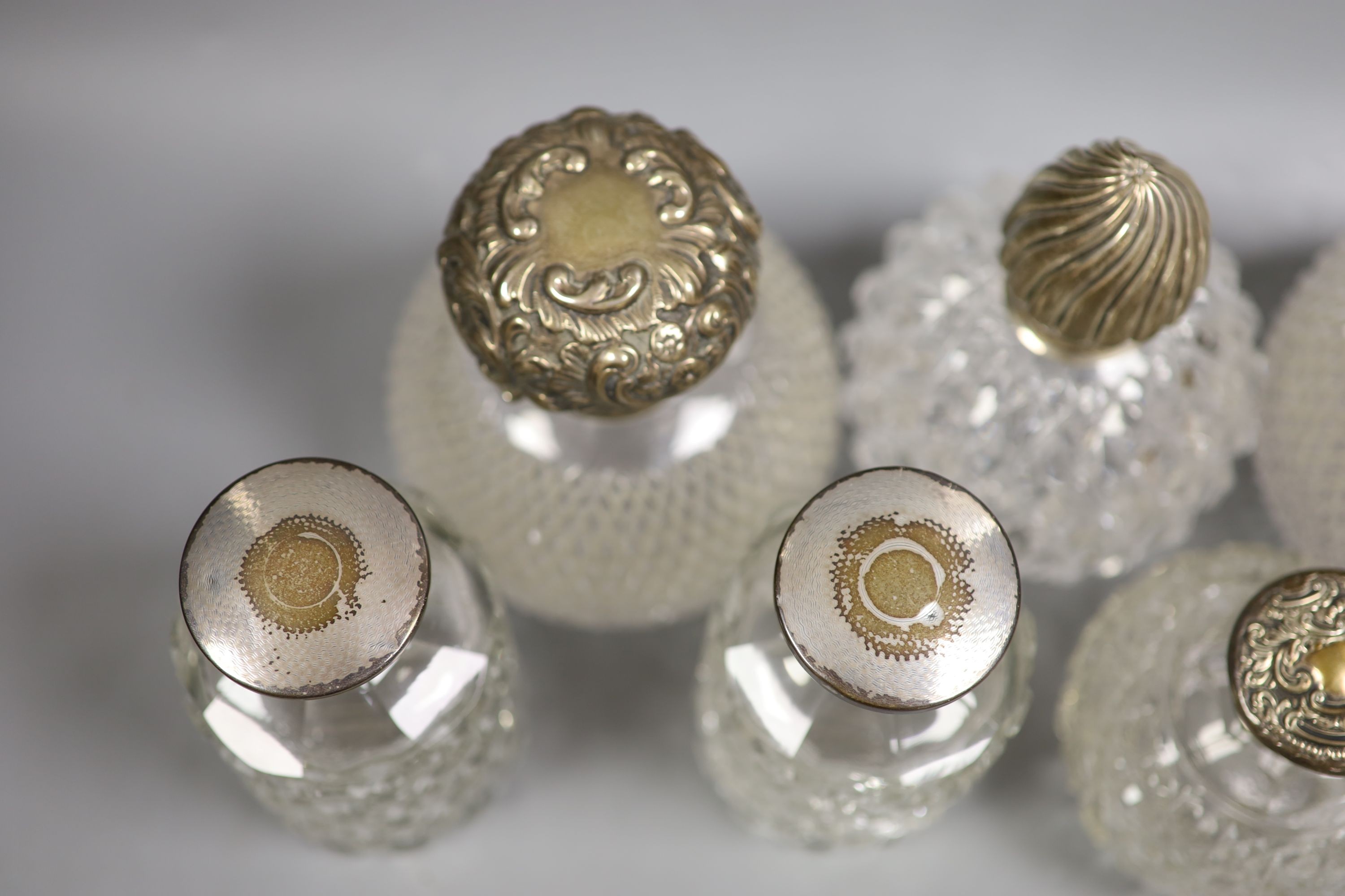 Six assorted silver topped glass scent bottles, including a pair by Chares Stuart Harris, London, 1899, height 14.4cm.